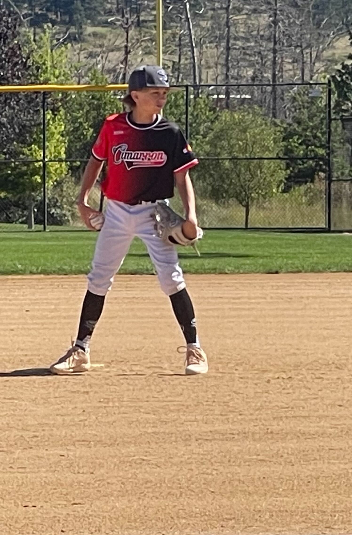 Baseball player in a black and red uniform set in a ready position on the infield
