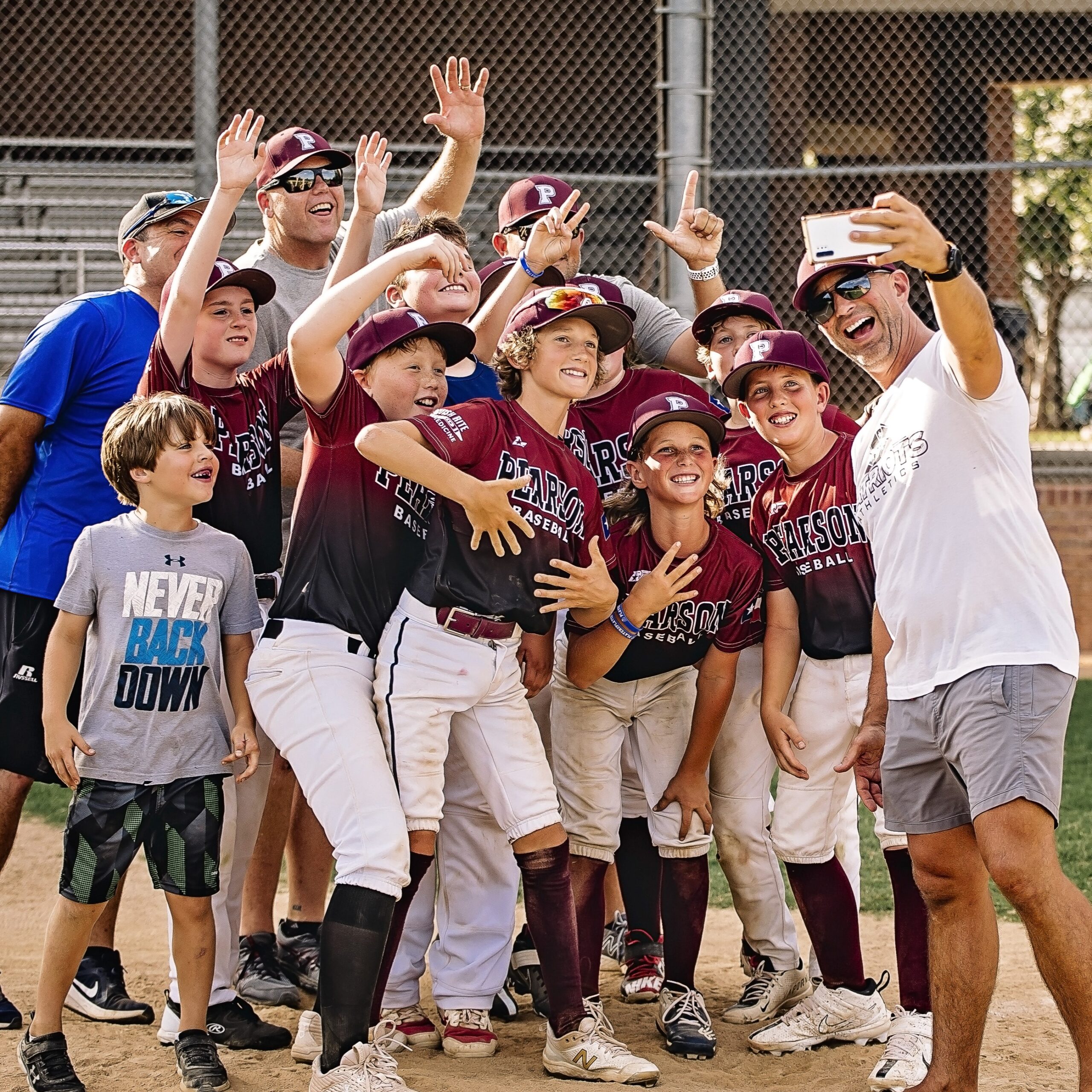 Baseball players and coaches in maroon uniforms smiling together at the field