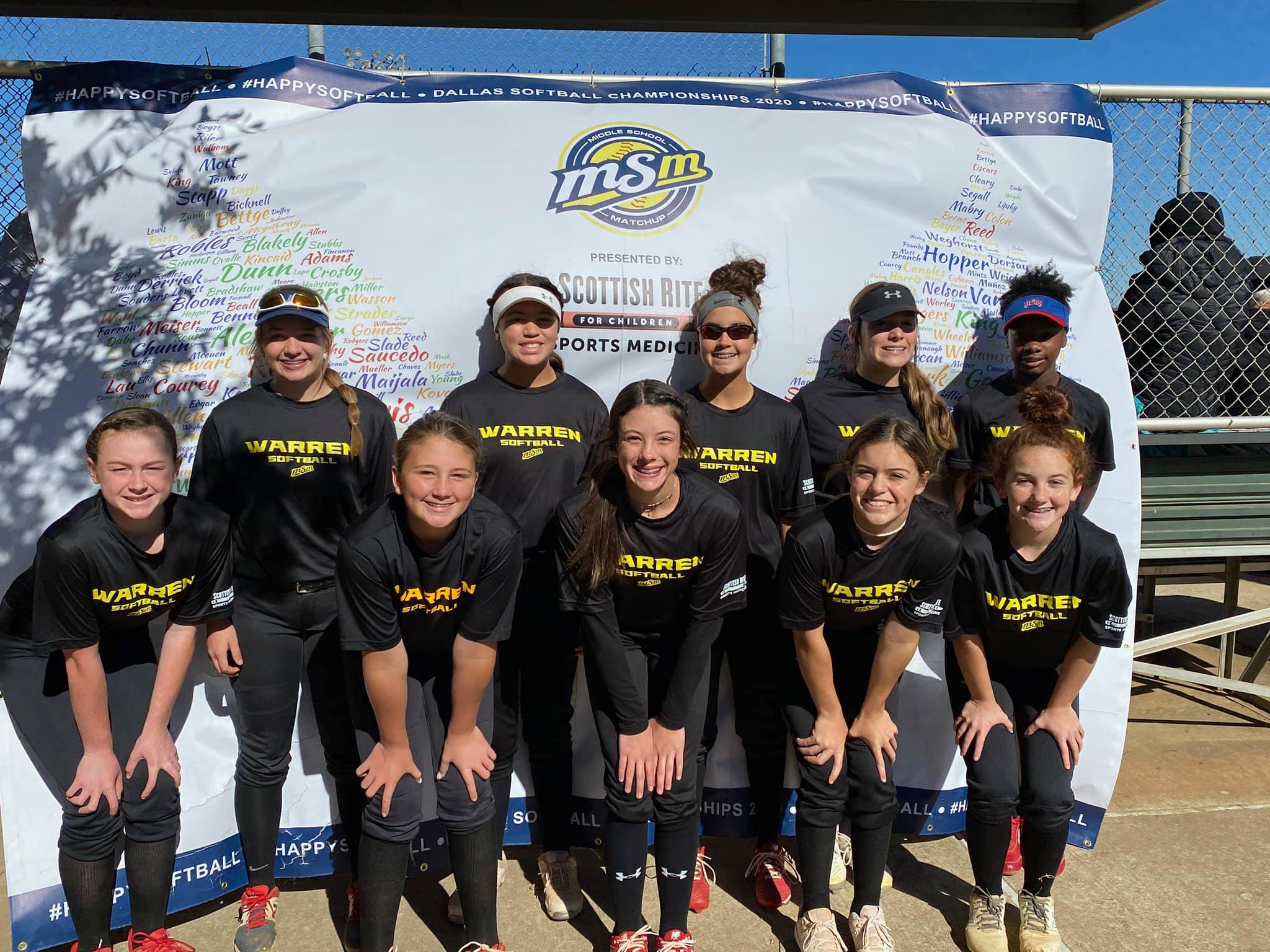Warren softball players gathered in front of a Middle School Matchup event banner